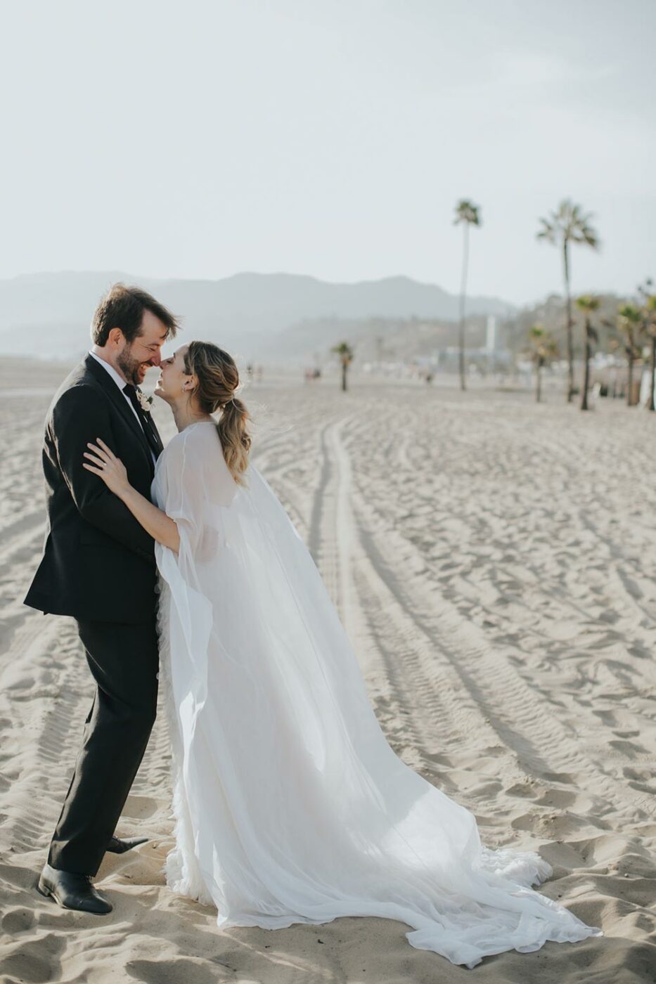 bridal cape and feathered wedding dress and black groom suit