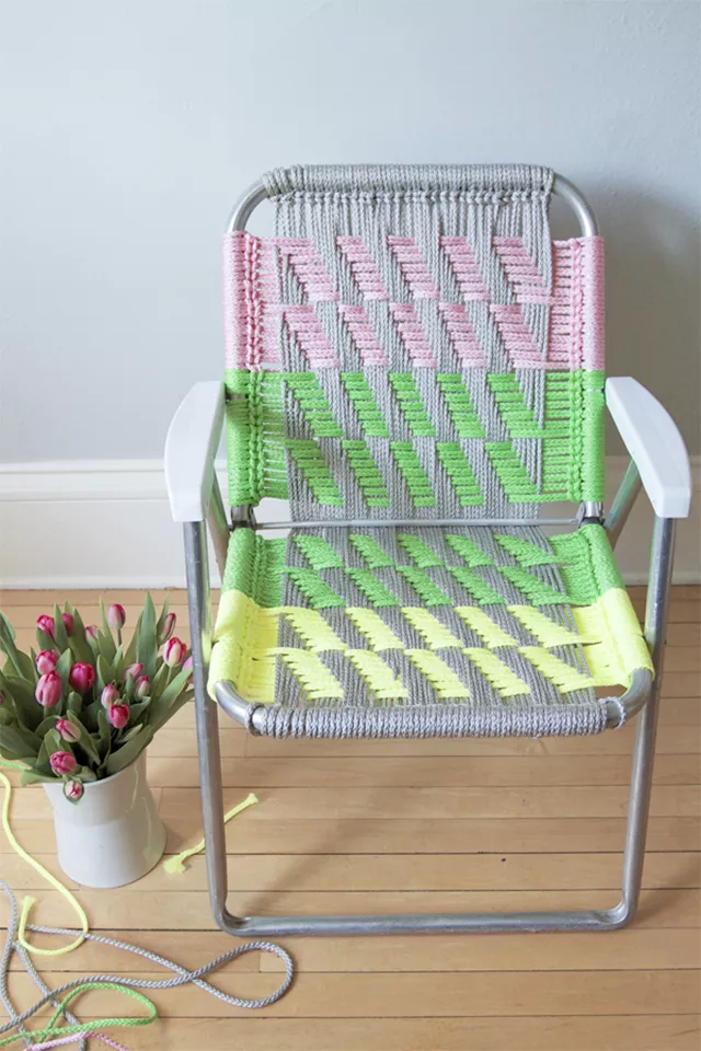 A macrame lawn chair in pink, green, and yellow