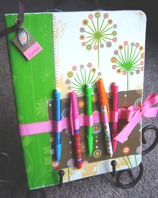 notebook decorated with ribbons, pens and scrapbook paper